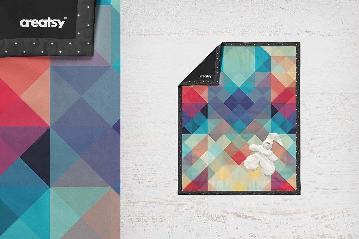 Baby quilt mockup featuring vibrant multicolor triangles, displayed flat with a small white plush bunny on top.