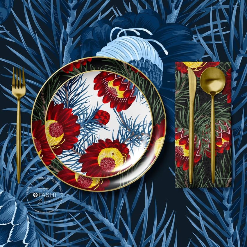 Placemat napkin plate mockup showing a floral plate and napkin with red protea flowers, gold cutlery, and a blue botanical background.