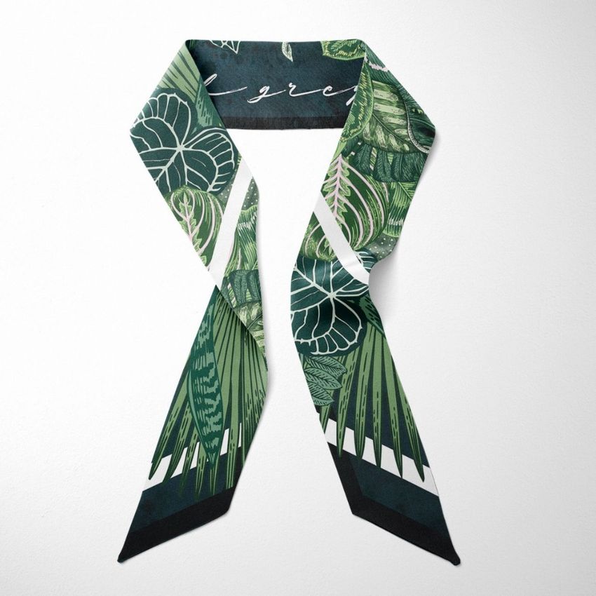 Top view of a twilly scarf mockup featuring a green botanical pattern with palm leaves on a white background.