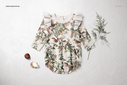 Knitted baby romper mockup with long sleeves, decorated with a detailed bird and leaf print, lying flat with props.