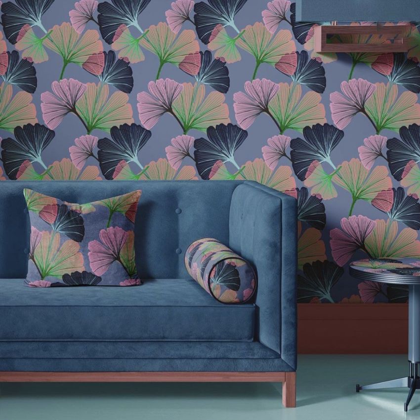 Velvet sofa and coffee table mockup featuring a blue sofa with patterned pillows, set against a wall with a ginkgo leaf design.