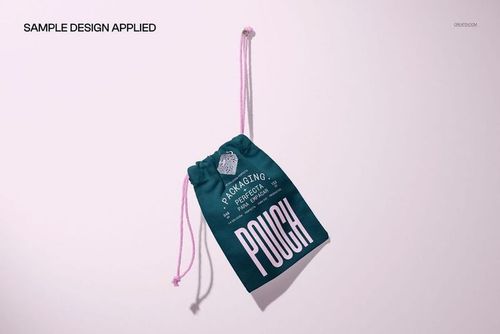Cotton drawstring pouch mockup featuring a dark green bag with pink strings and bold white lettering, angled on a pale surface.