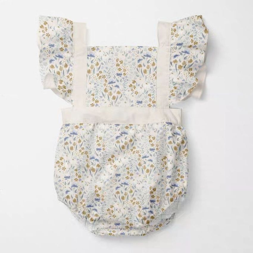 Baby romper mockup featuring a floral pattern in soft blue, yellow, and beige tones, displayed flat on a white background.