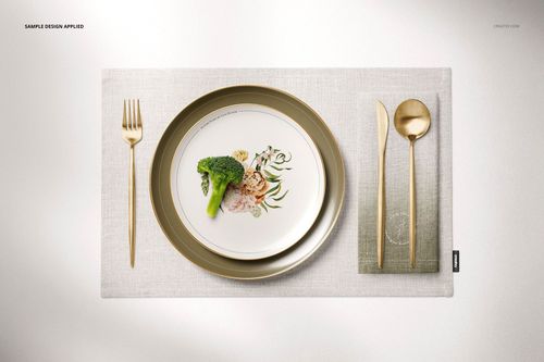 Flat lay of a home dining scene showing a plate with floral design, gold fork and knife, and a gray placemat mockup.