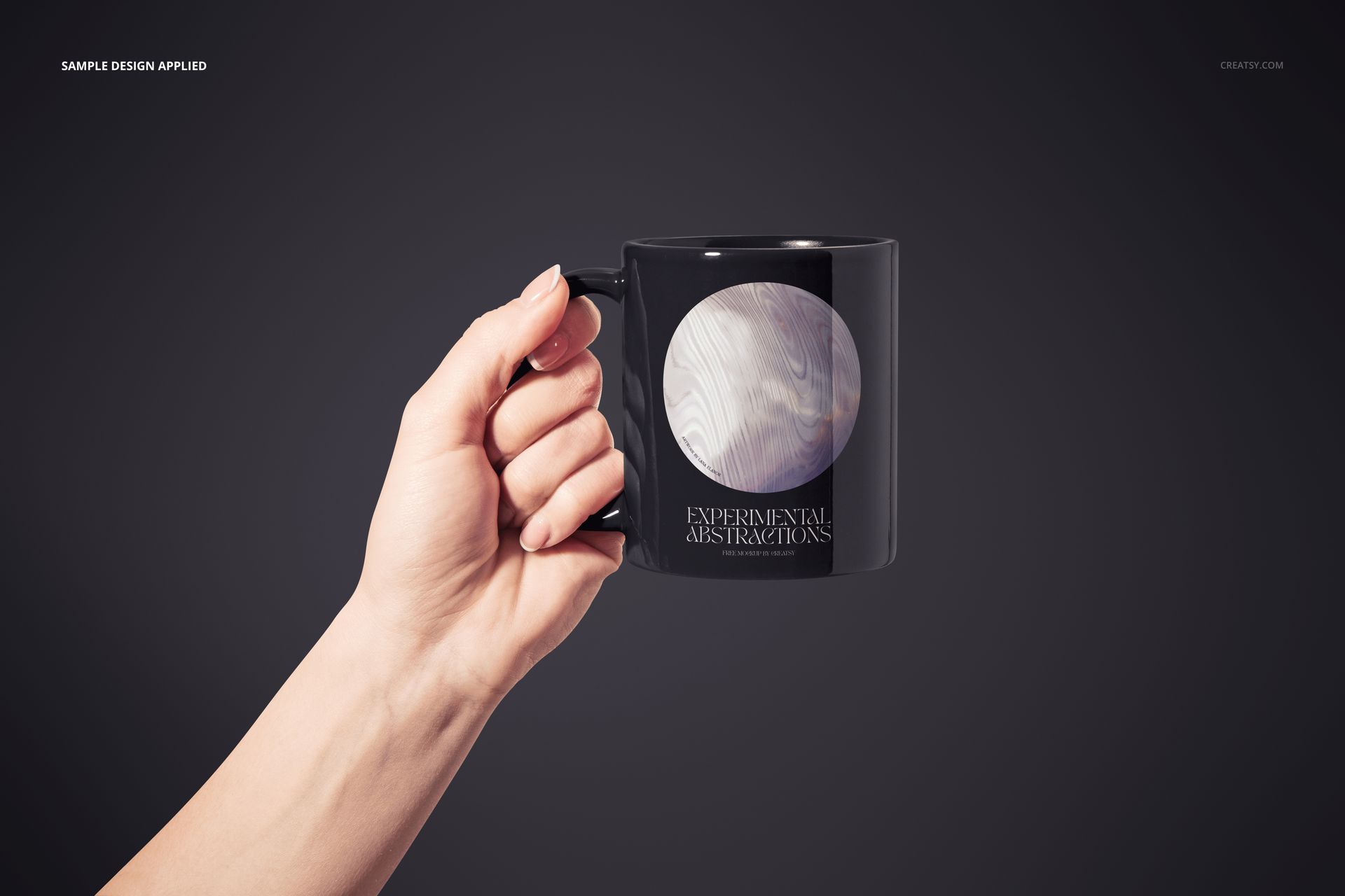 Black custom mug mockup held in a hand, displaying a round artistic pattern and minimal lettering, with a neutral background.