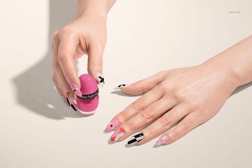 PSD mockup showing hands with creative nail art in black, pink, orange, and white, set against a neutral surface.