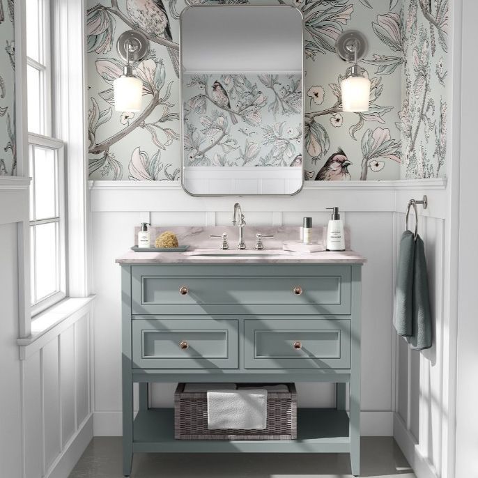 Bathroom mockup showing a blue vanity with marble countertop, mirror, and bird-patterned wallpaper in soft pastel tones.