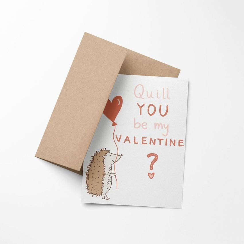 A2 card mockup featuring a white card with a hedgehog illustration holding a heart balloon and playful text, next to a brown envelope on a white background.