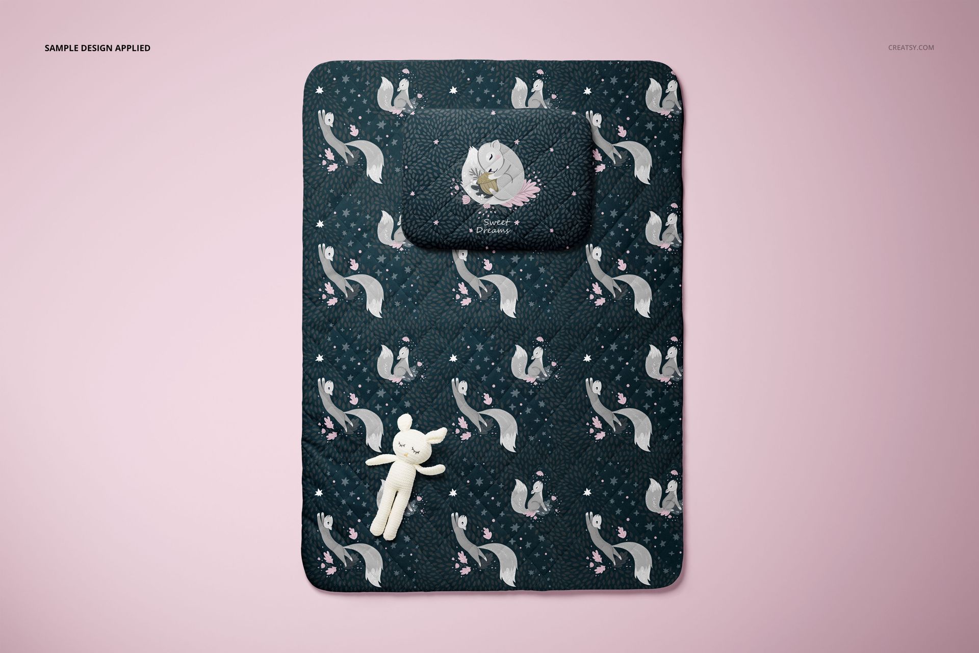 Mockup of a baby bedding set with pillow and quilt, dark design with animal motifs, displayed from above.
