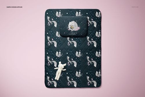 Mockup of a baby bedding set with pillow and quilt, dark design with animal motifs, displayed from above.