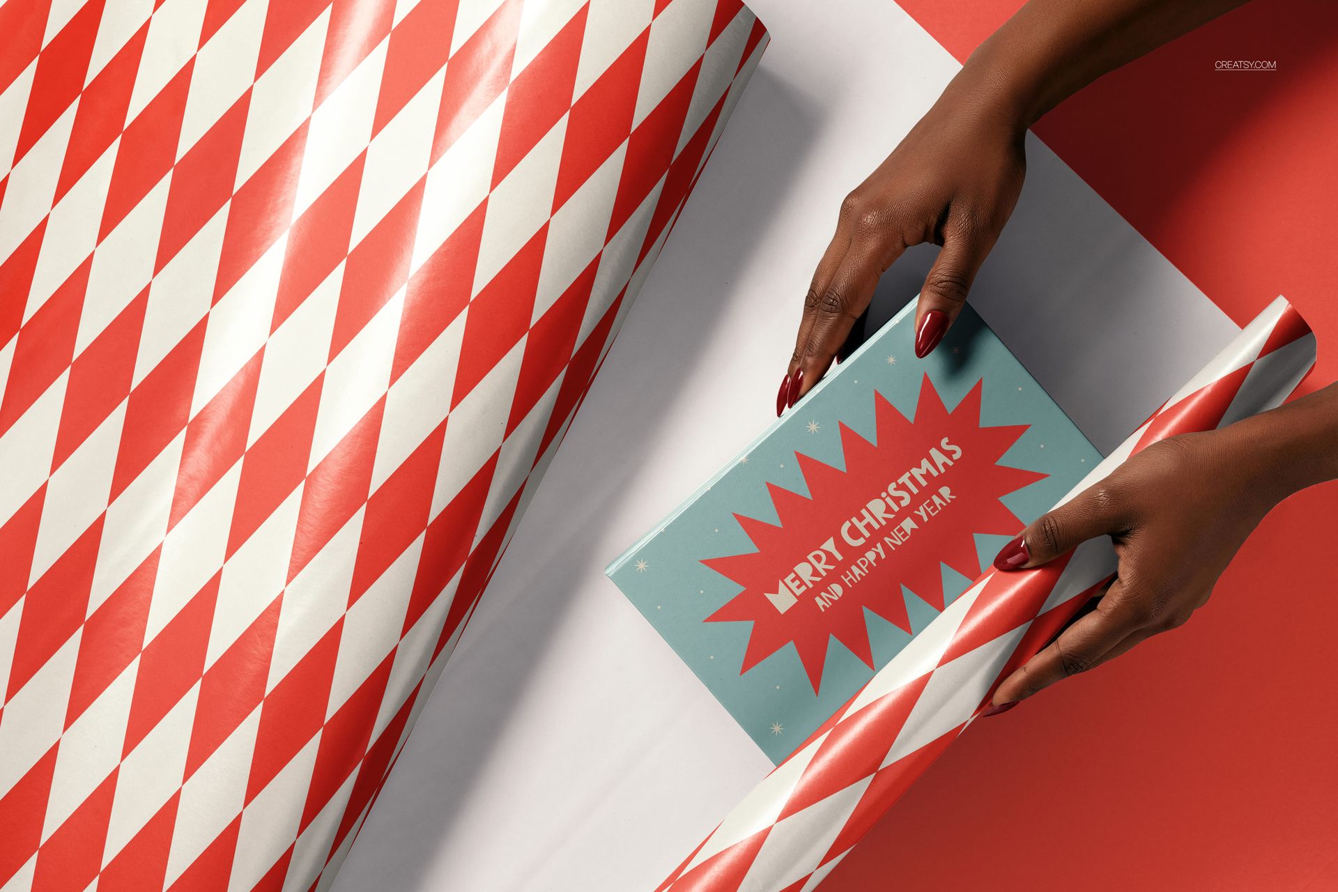 Christmas PSD mockup showing a gift being wrapped with geometric patterned paper and a greeting card nearby.