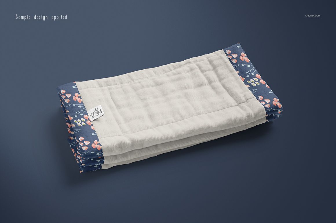 Folded burp cloth mockup with a quilted cream center and blue edges featuring a pink floral pattern on a dark background.
