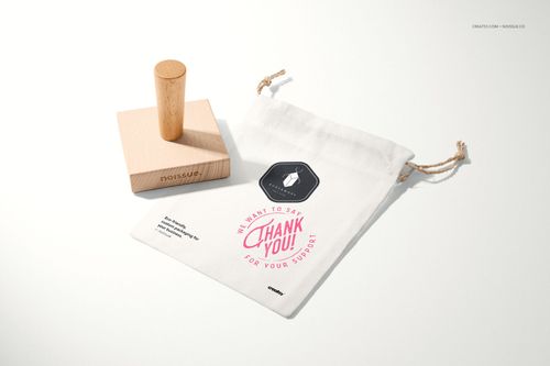 Stationery mockup showing a wooden stamp and a white pouch with a thank you message and decorative graphics on a light surface.