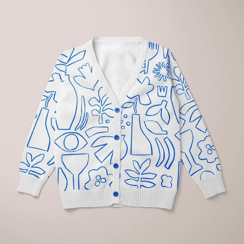 Baby cardigan sweater mockup featuring a white knit sweater with bold blue abstract line art and button details on a light background.