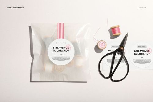 Glassine bag mockup featuring a circular sticker, with sewing tools and thread spools arranged on a white background.