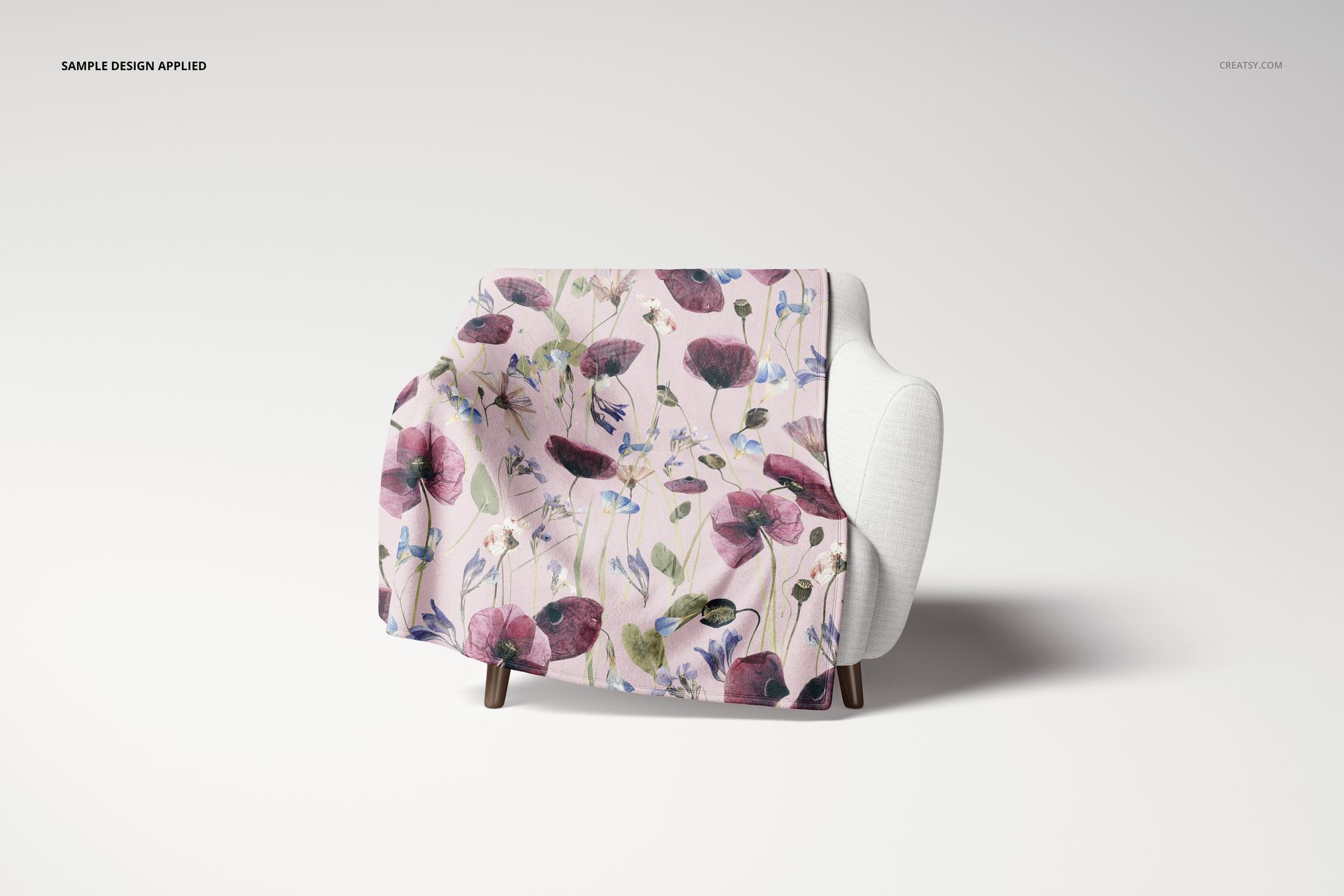 Fleece blanket mockup featuring purple and pink flowers, displayed on a modern white chair against a white backdrop.