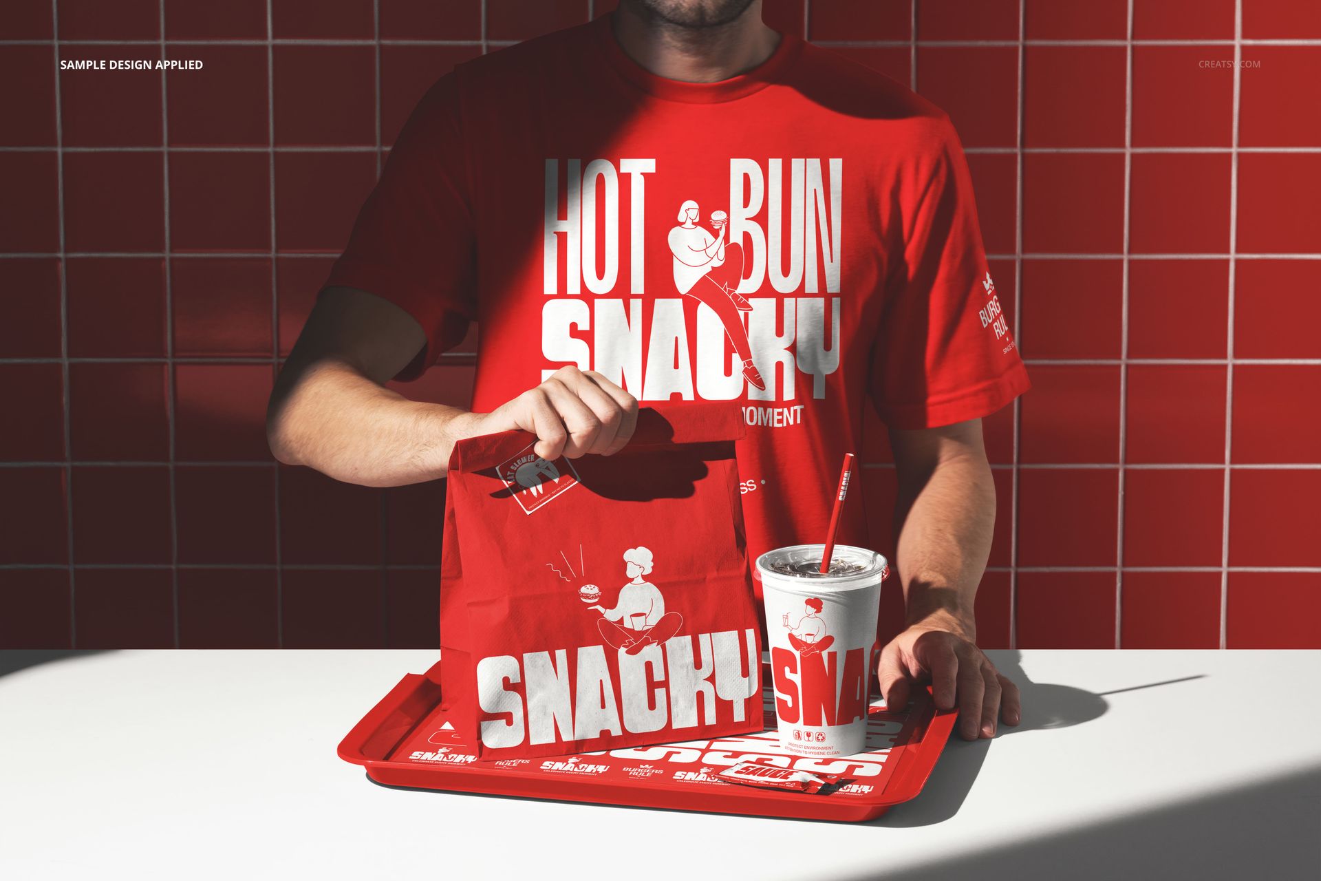 Red fast food packaging mockup featuring a man in a graphic t-shirt, tray, bag, and cup on a white counter.
