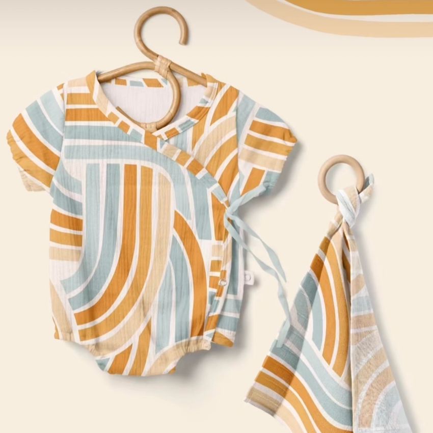 Muslin onesie mockup featuring a short-sleeve baby bodysuit and matching cloth, both with geometric stripes in orange, beige, and teal.