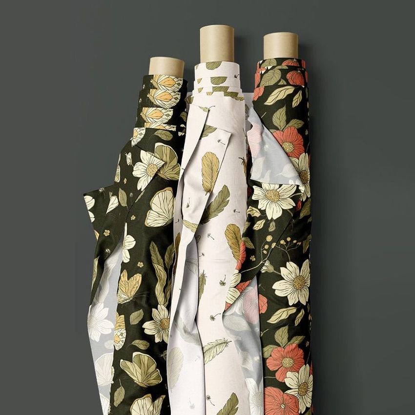 Fabric rolls mockup featuring three upright rolls with floral and bird patterns in muted green, cream, and coral tones on a gray background.