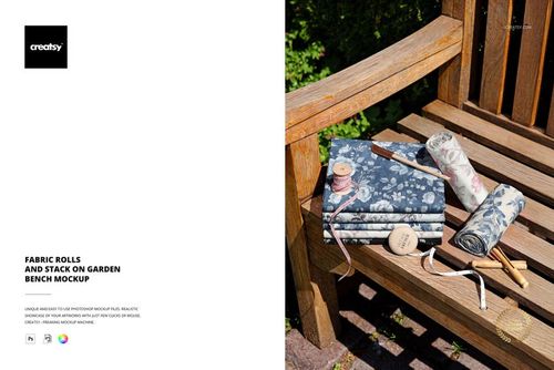PSD mockup showing patterned fabric rolls and stacks placed on a rustic wooden bench in a garden setting.
