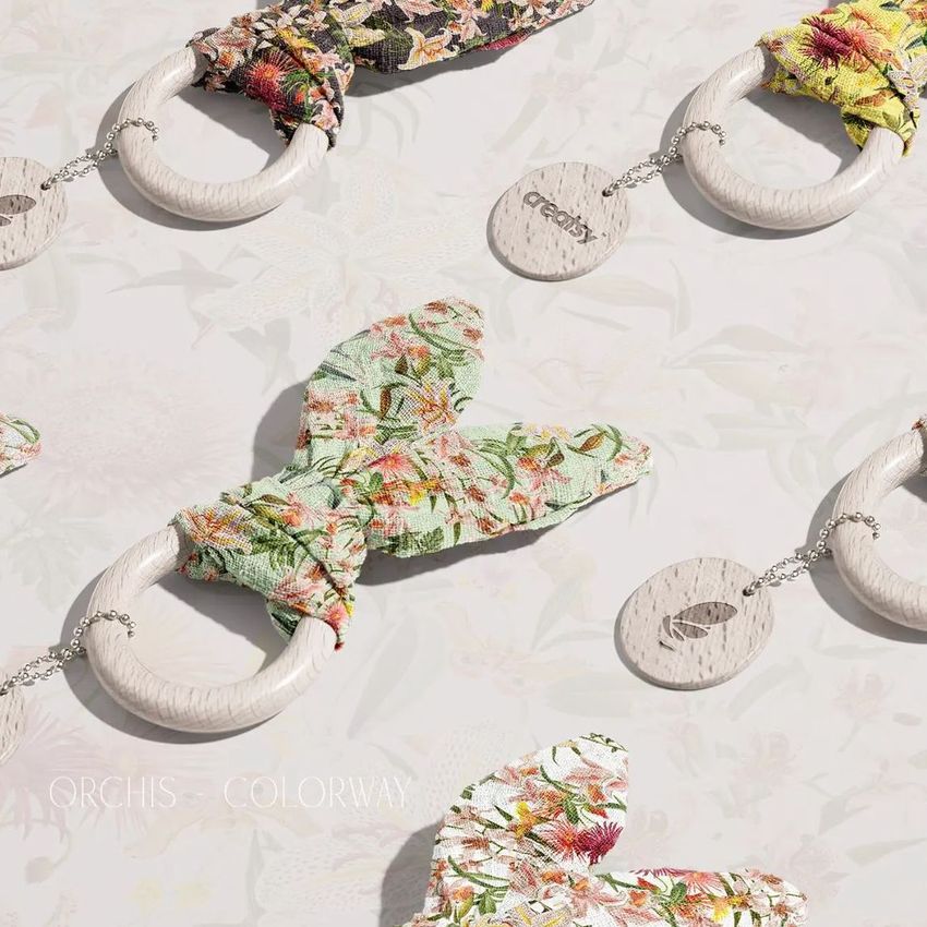 Wooden baby teether mockup set displayed on a light floral background, featuring fabric bunny ear accents in various patterns.