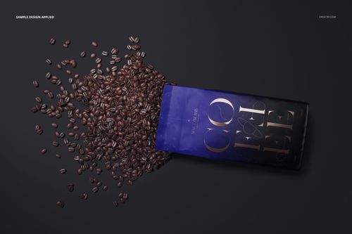 Matte coffee bag mockup lying on a dark surface with coffee beans spilling out, front angled view.