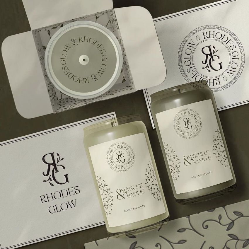 Can glass candle mockup set featuring two candles with elegant labels, a branded box, and matching printed cards on a neutral surface.