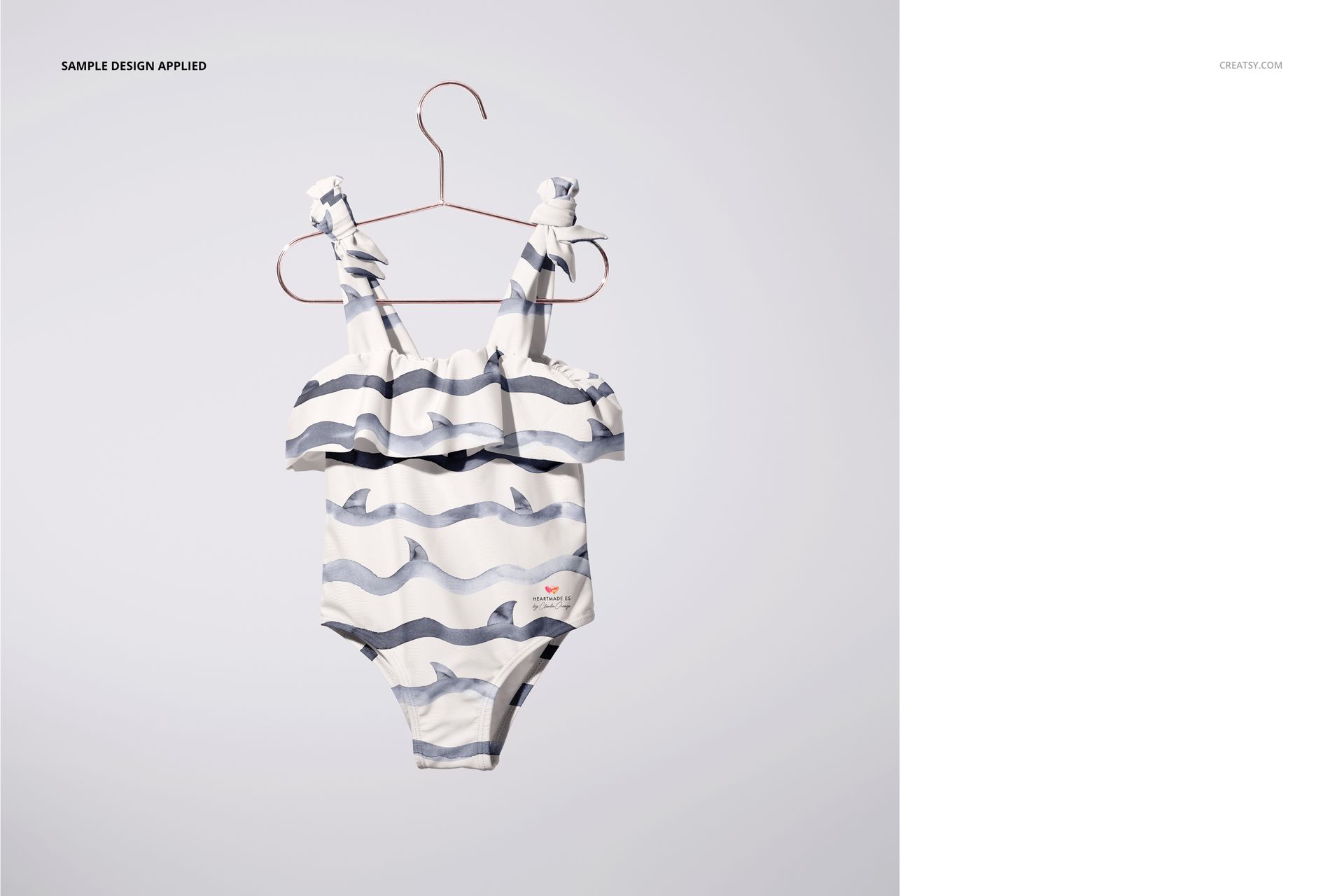 Front view of a striped baby swimsuit mockup with ruffle detail, displayed on a hanger over a plain white surface.