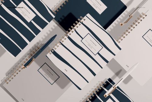 PSD mockup showing multiple little coiled notebooks with striped patterns and gold spirals on a neutral background.