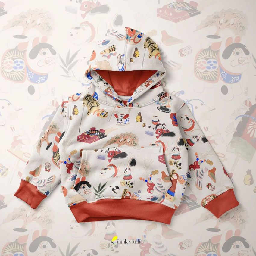 Kids pull on hoodie mockup featuring playful, colorful illustrations on a light background, laid flat with matching backdrop.