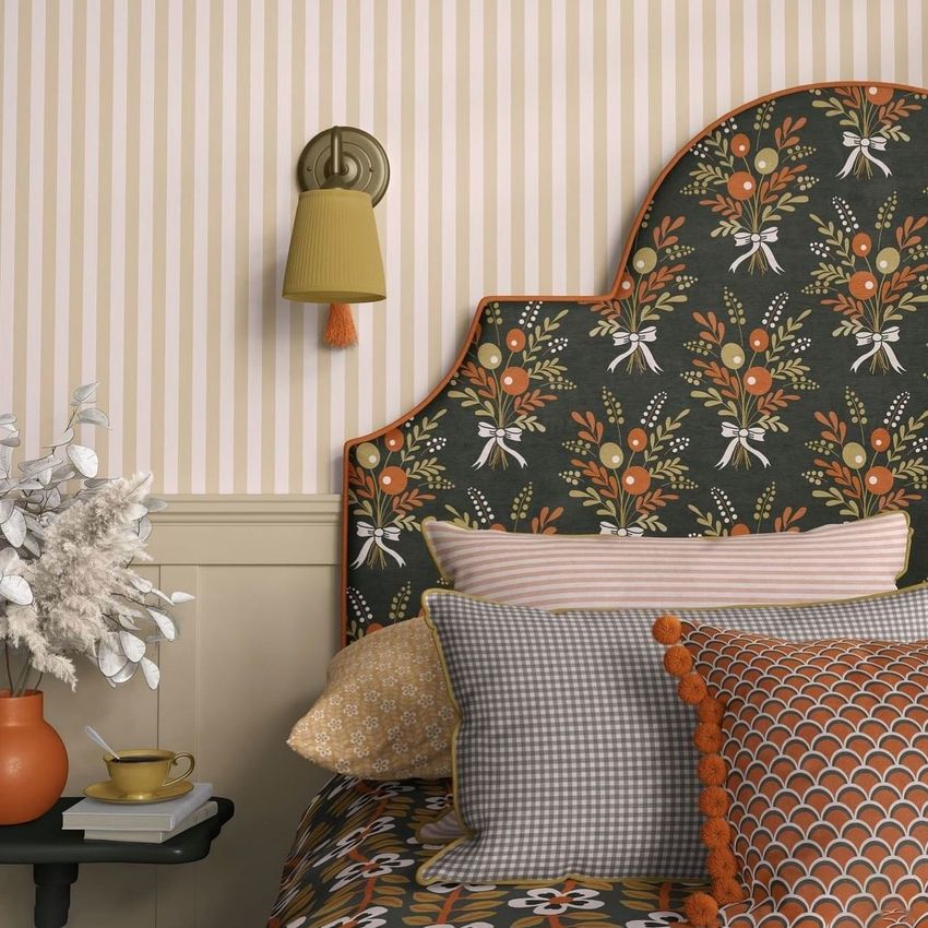 Bedroom mockup featuring patterned pillows, a floral headboard, and striped wallpaper in warm autumn tones with a wall sconce.