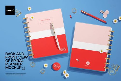 Spiral planner mockup showing both front and back covers in pink and red, surrounded by pens and clips on a blue background.