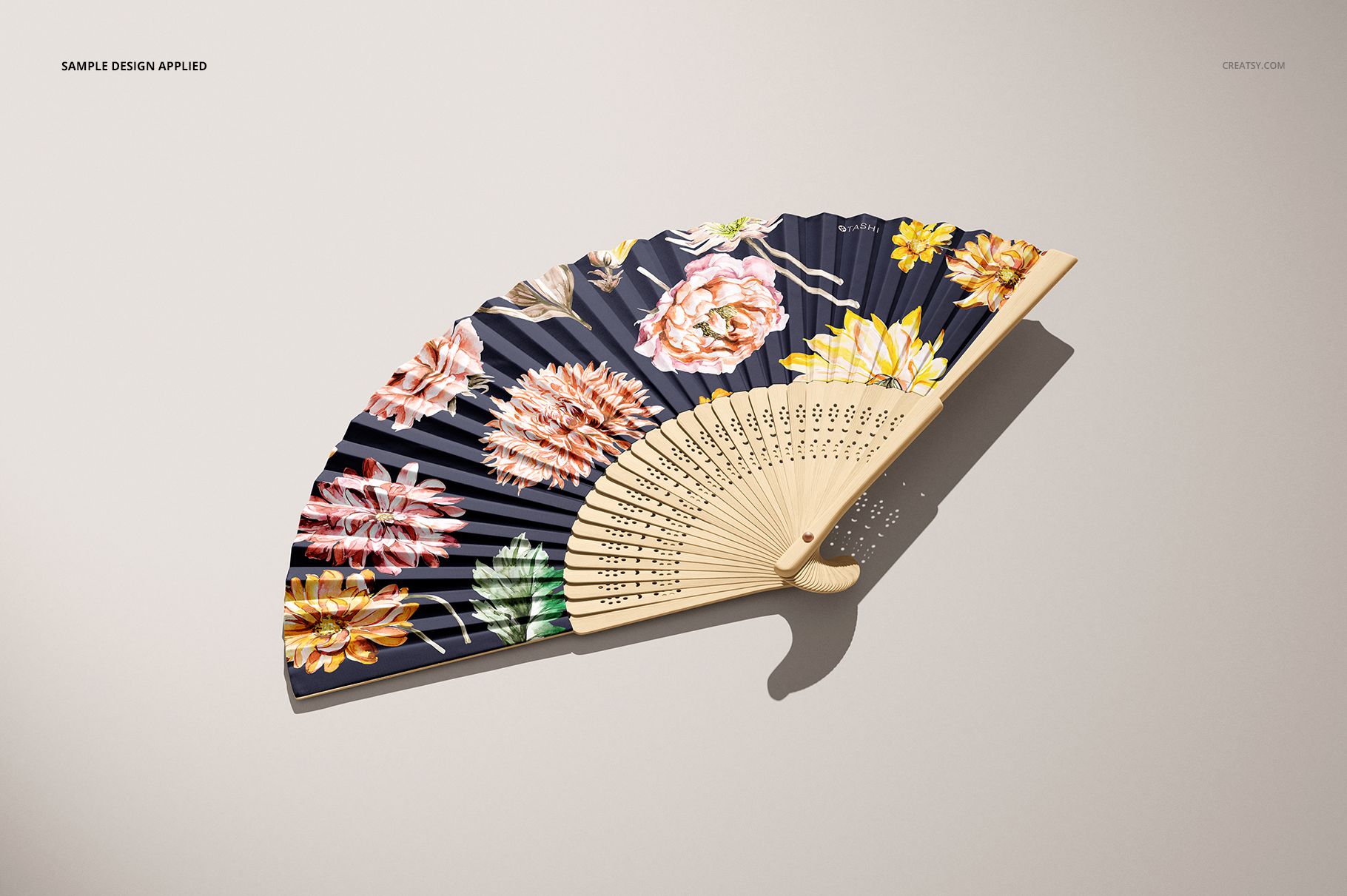 PSD mockup of a fabric hand fan with wooden ribs, decorated with large colorful flowers on a navy fabric.