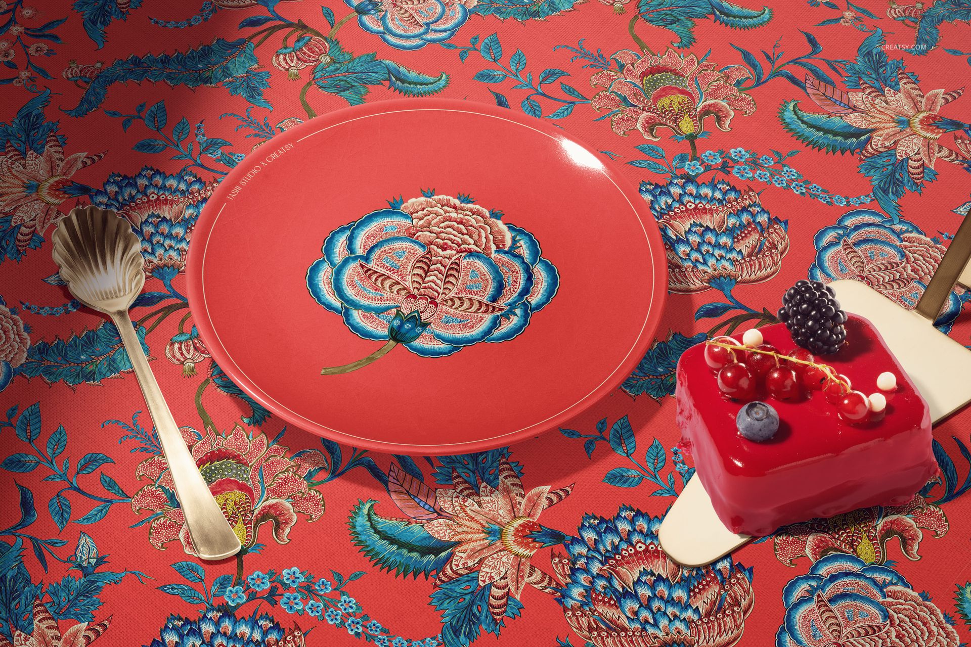 PSD mockup featuring a ceramic plate with ornate flower artwork, accompanied by gold utensils and a berry-topped dessert.