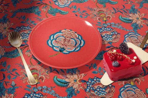PSD mockup featuring a ceramic plate with ornate flower artwork, accompanied by gold utensils and a berry-topped dessert.