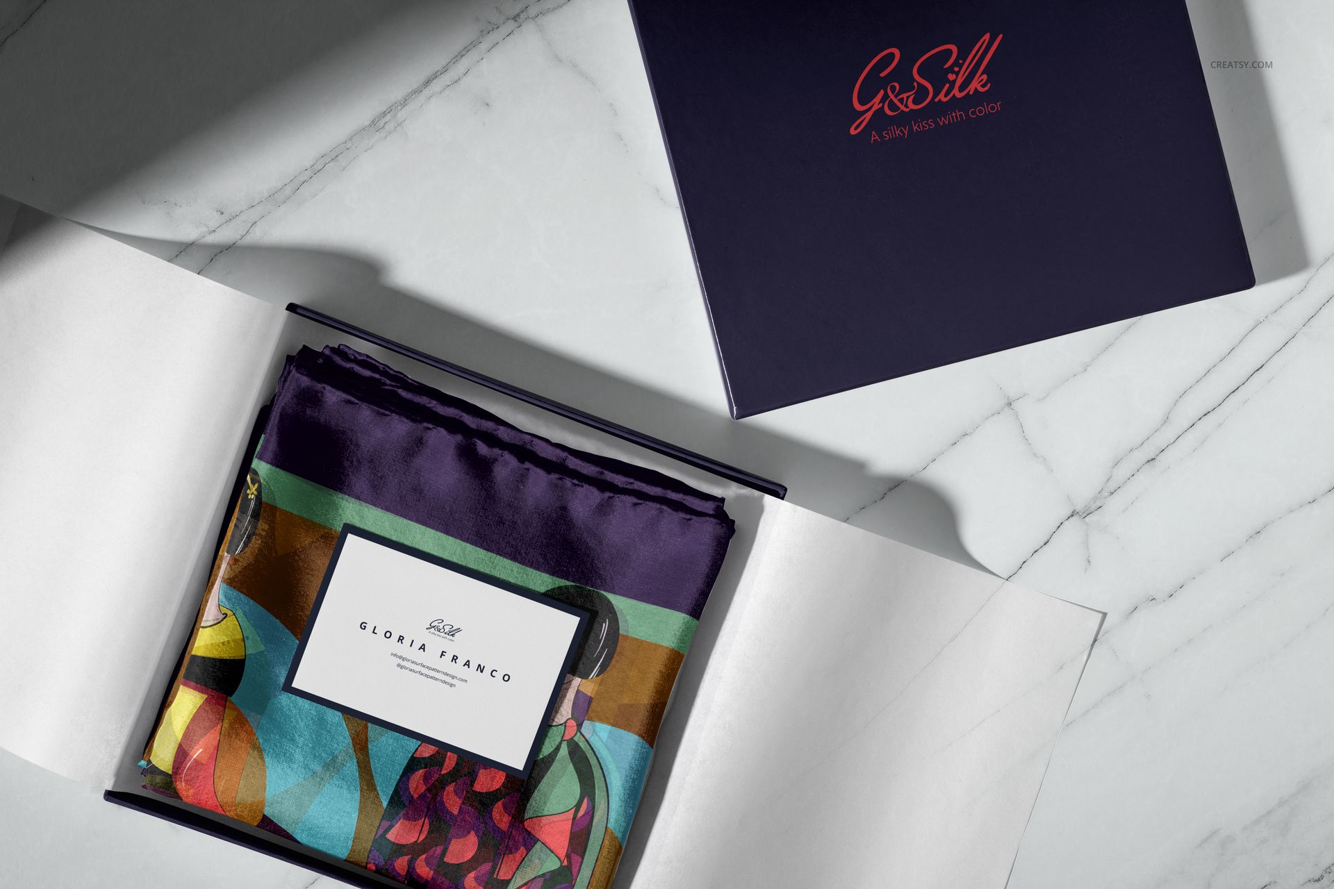 PSD mockup showing a vibrant silk scarf with multicolored design, packaged in a luxury box with visible branding.