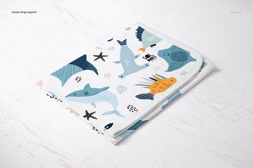 Cotton baby blanket mockup featuring playful aquatic animal patterns, displayed folded on a light wooden background.