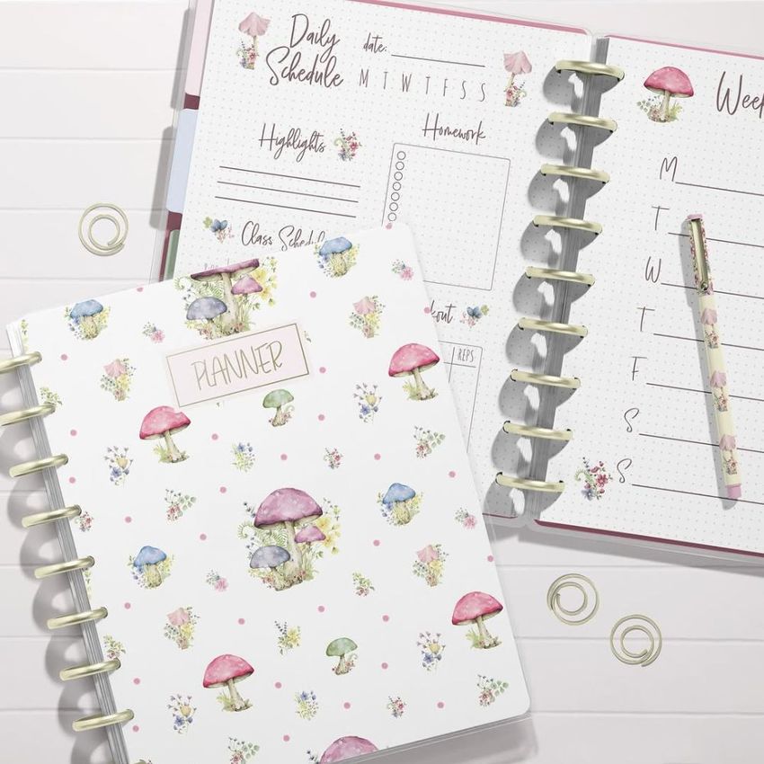 Top view of two spiral planners on a white surface, one closed with a mushroom pattern cover and one open to a weekly layout.