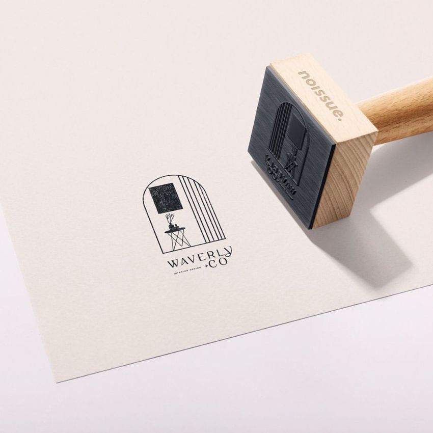 Wooden stamp mockup on light paper, showing a stamped logo design with black ink and minimal modern graphics.