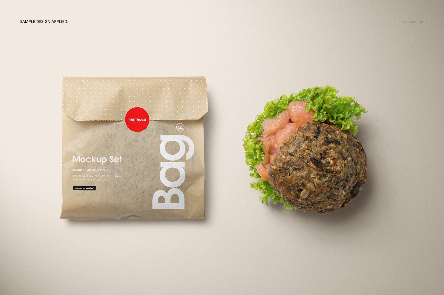 Top view of a brown paper snack bag mockup with red sticker seal, placed beside a fresh sandwich on beige surface.