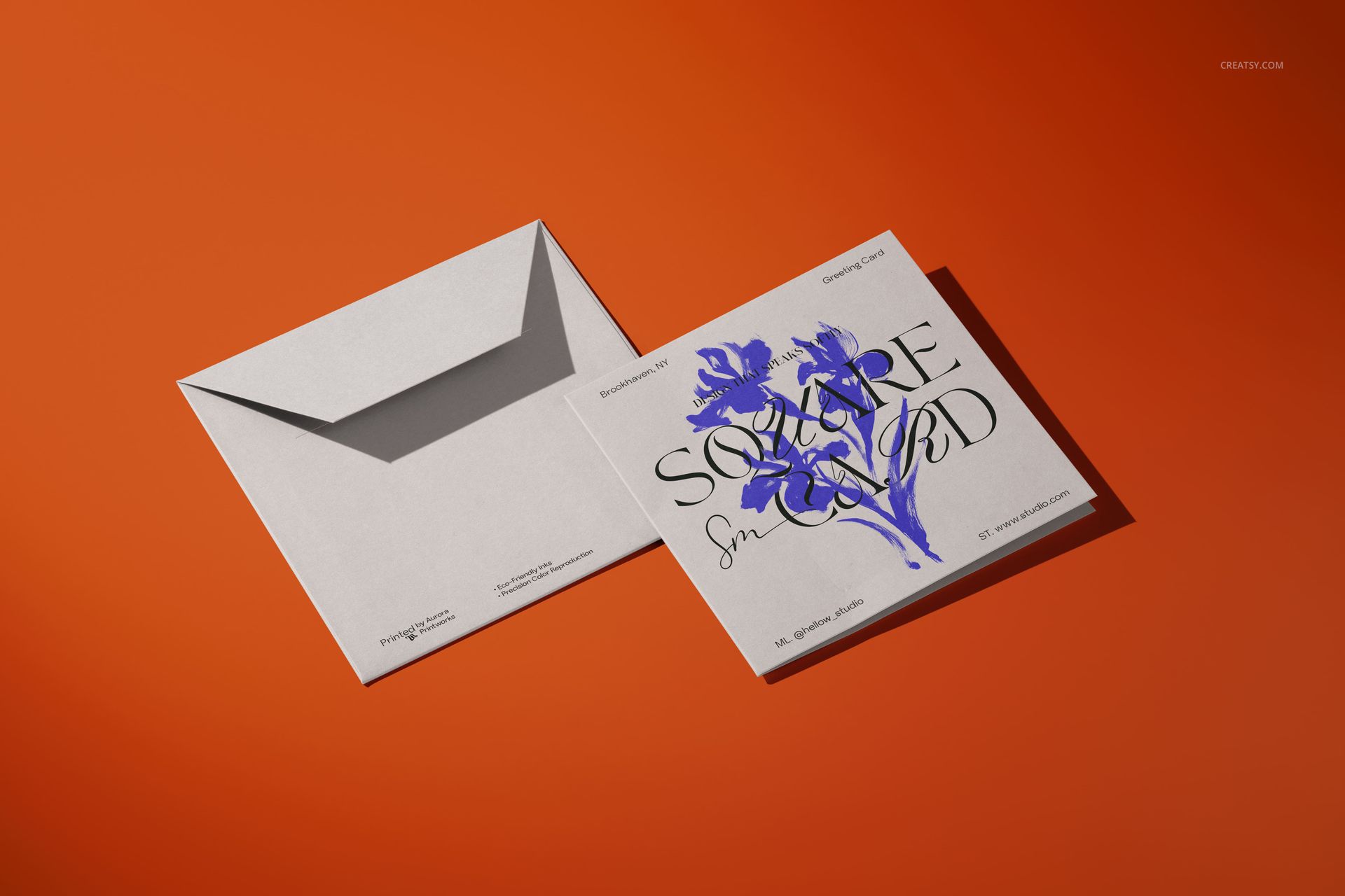 Front view of a square greeting card mockup with blue flower illustration and gray envelope on an orange background.