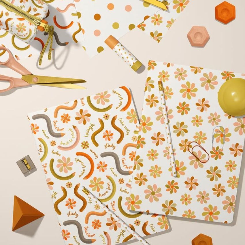Stationery mockup featuring two classic A4 notebooks with floral and wavy line patterns, surrounded by pencils, scissors, and geometric props on a light surface.