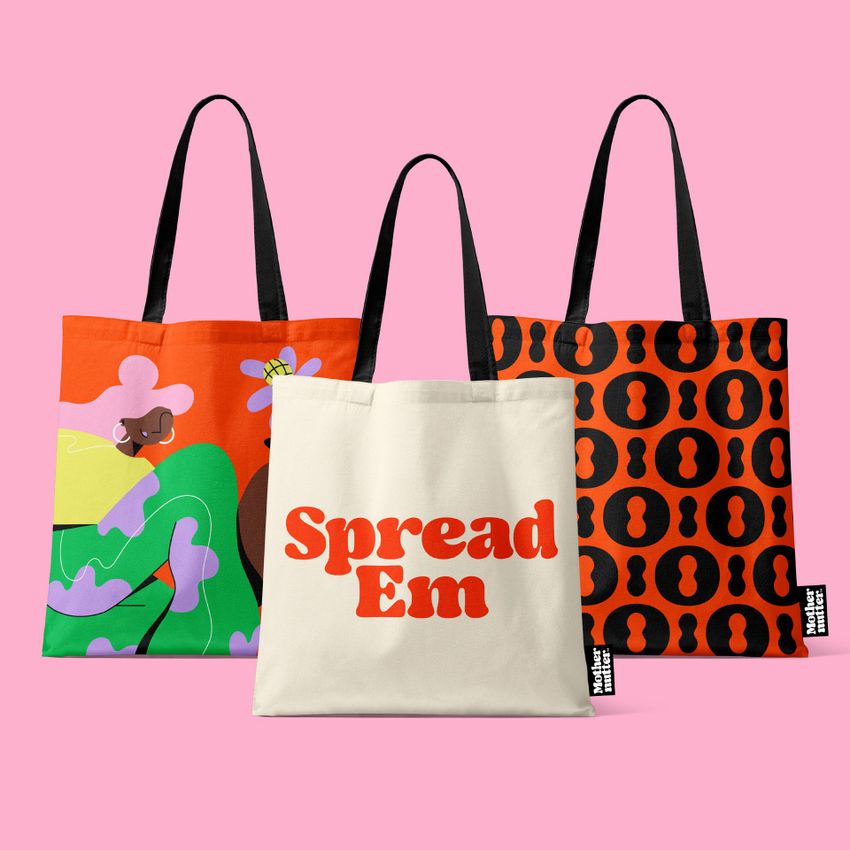Tote bag mockup featuring three bags standing upright on a pink background, each with a distinct colorful pattern or text.