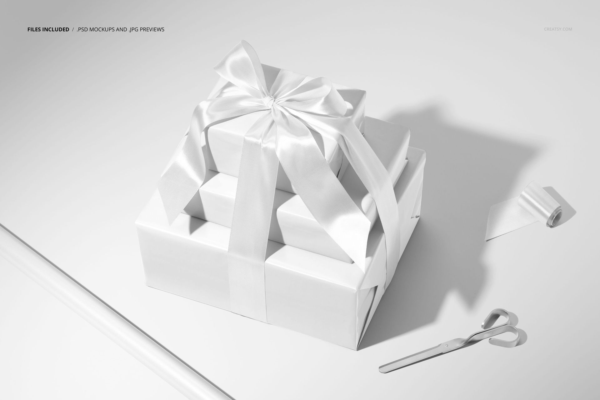 PSD mockup showing three neatly wrapped holiday gifts with a large bow, surrounded by a roll of paper, ribbon, and silver scissors.