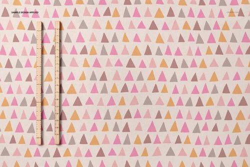 Top view of jersey fabric mockup with pink, orange, and brown triangle pattern and two wooden rulers.