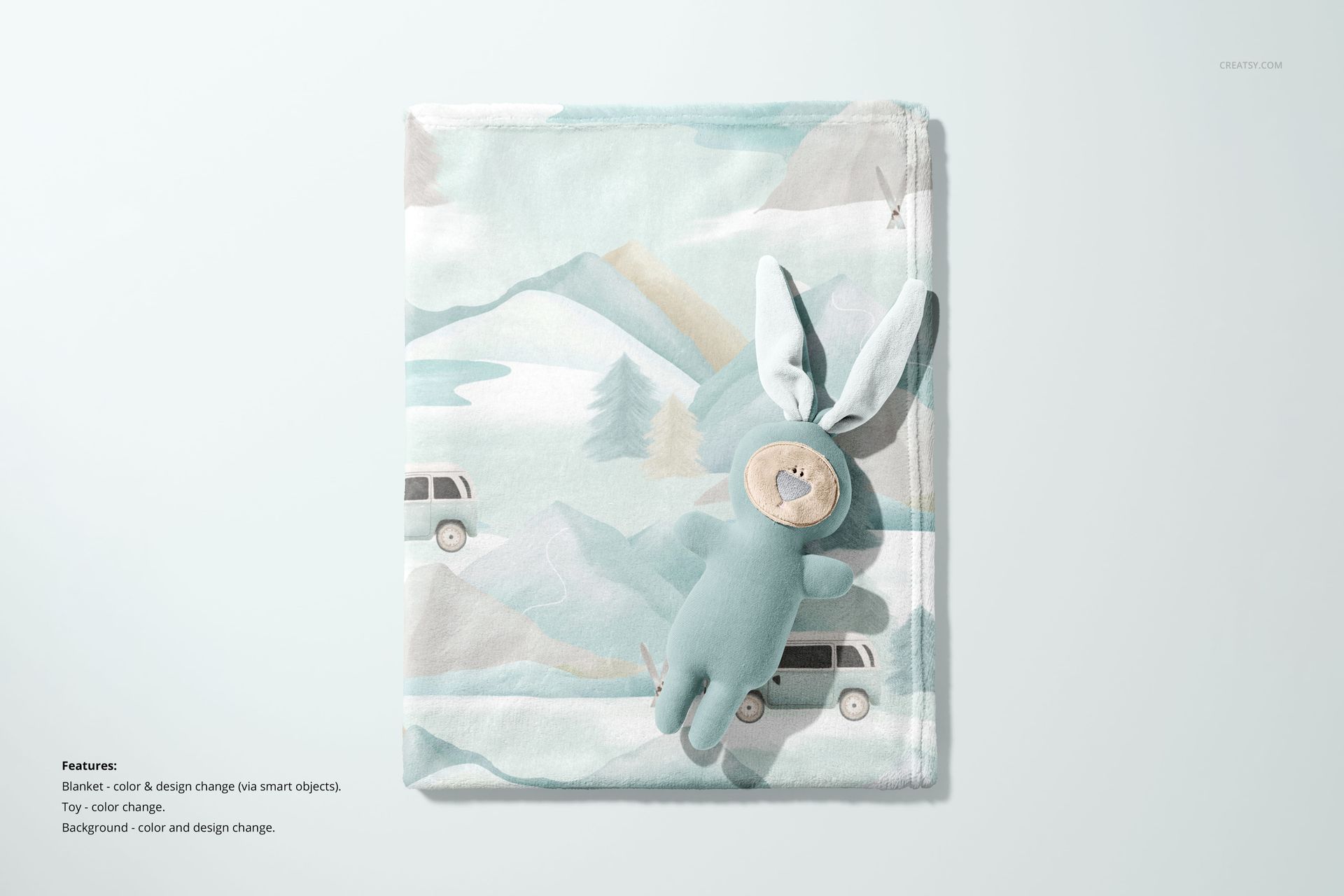 PSD mockup showing a folded kids fleece blanket with muted colors and a bunny plush, arranged on a light background.