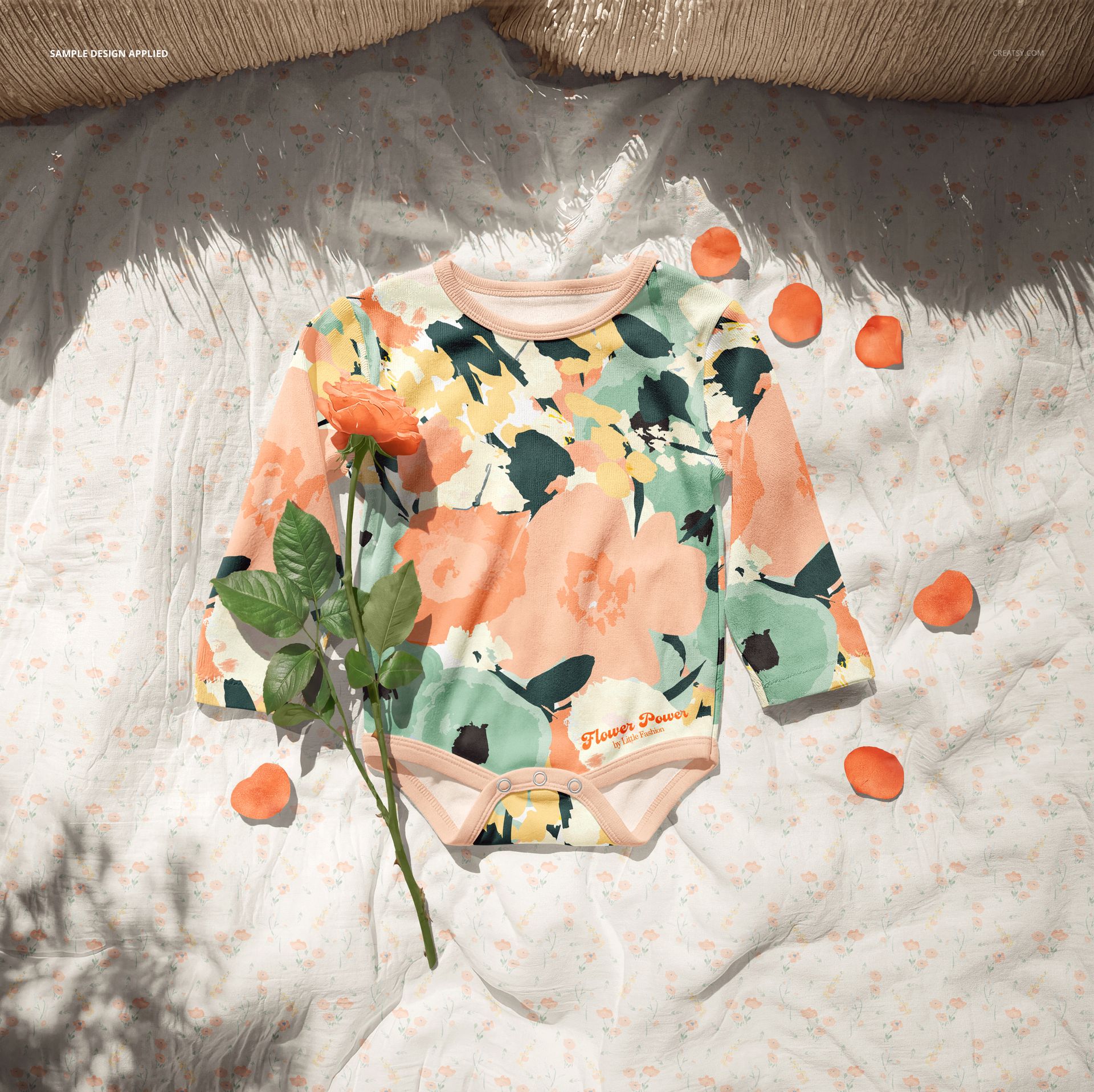 PSD mockup of a long-sleeve baby growsuit featuring abstract rose designs in pastel tones, surrounded by rose petals.