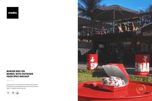 Open burger box mockup displayed on a red barrel outside, featuring food wrapping and a casual outdoor dining area.