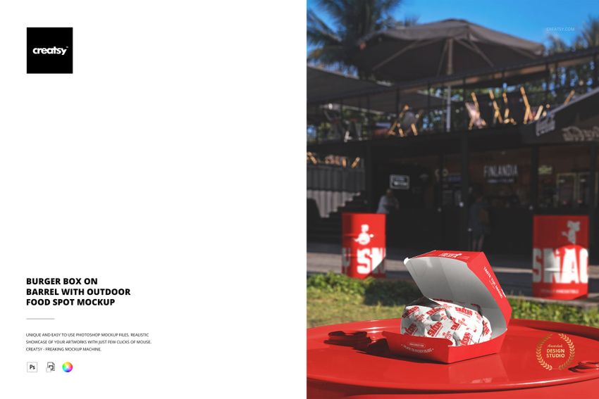 Open burger box mockup displayed on a red barrel outside, featuring food wrapping and a casual outdoor dining area.