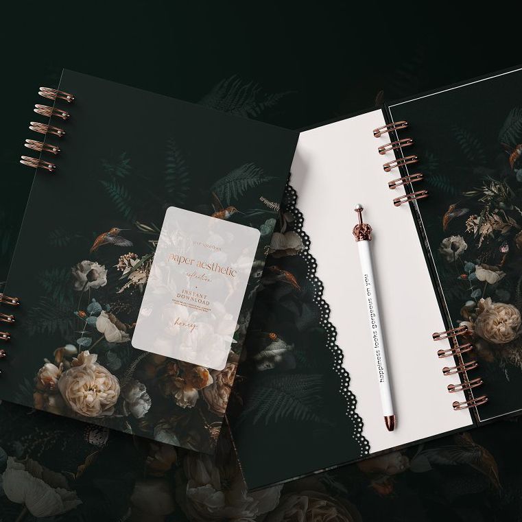 Planner mockup featuring two spiral-bound notebooks with dark floral covers and a white pen on a dark surface.